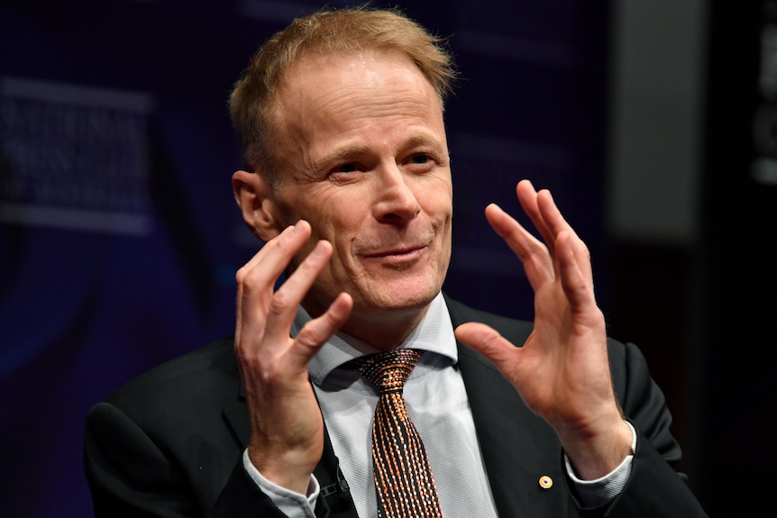 Richard Scolyer holds up his hands while speaking at the National Press Club