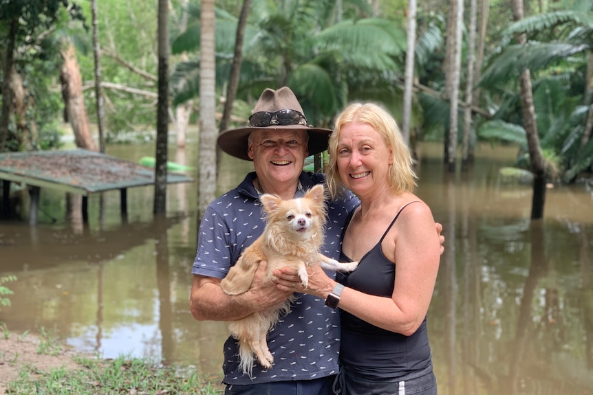 A couple and their dog on a flooded property.