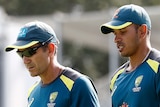 Australia men's cricket coach Justin Langer and player Usman Khawaja walk around Manuka Oval in their warm-up gear.