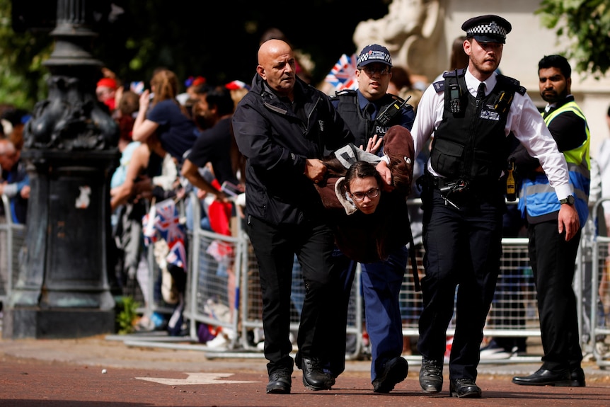 Police officers carry a protester who interrupted Trooping the Color in London.