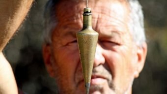 Close up of man holding a conical pendulum up in front of his face.