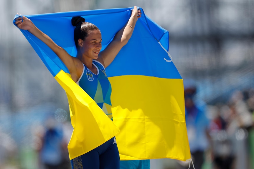 A female Ukrainian Olympic athlete holds the country's flag after wining bronze.