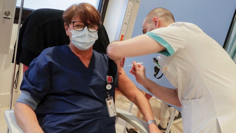 A nurse gets a coronavirus vaccine injection by a doctor in hospital