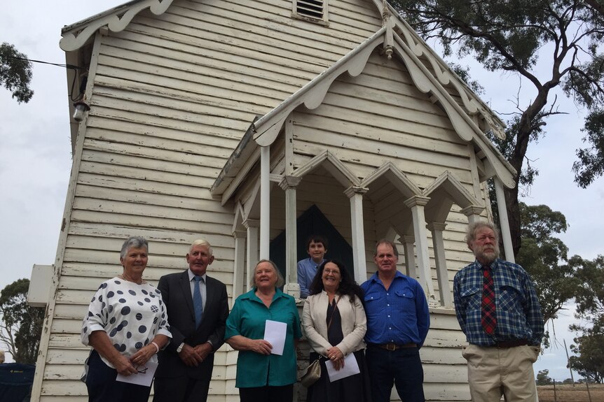 Seven people standing outside a white church