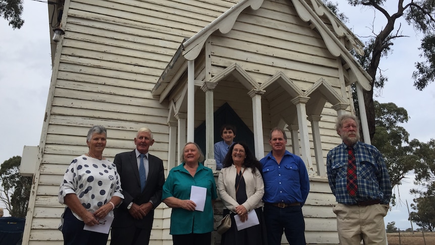 Seven people standing outside a white church