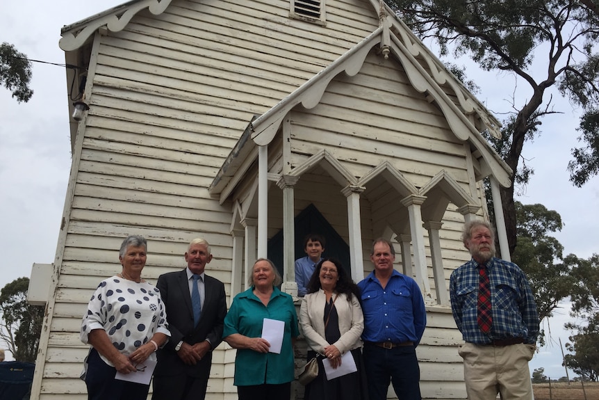 Seven people standing outside a white church