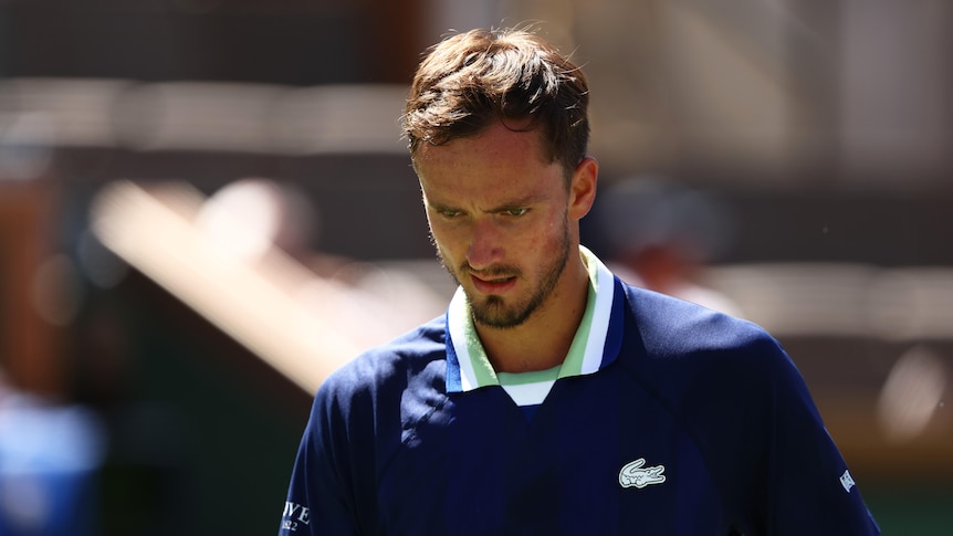 A tennis player stares down at the court while down in a very important match.