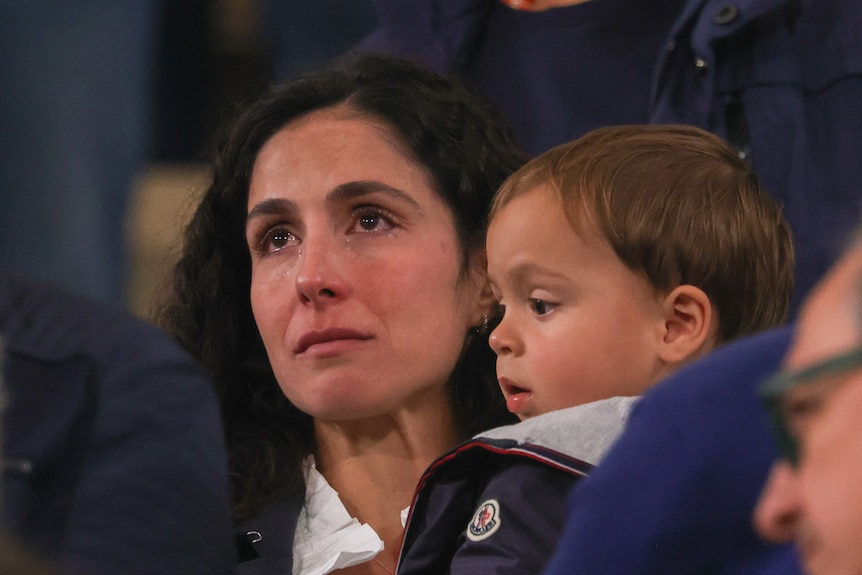 Maria Perello cries as she holds Rafael Nadal Jr in the stands during Rafael Nadal's final match at Roland Garros.