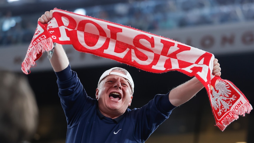 A Polish fan holds up a scarf reading "POLSKA" in support of tennis player Iga Swiatek during her match at Roland Garros.