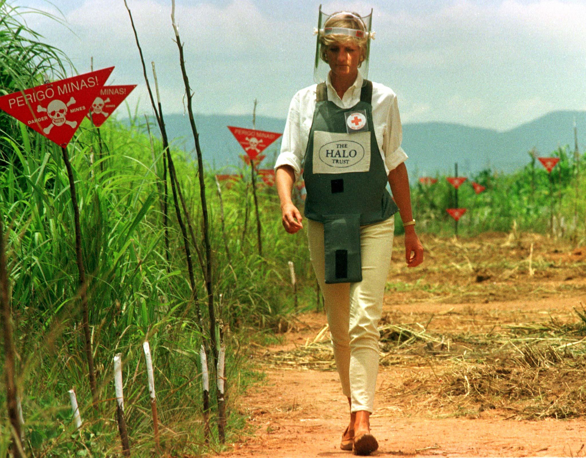 Princess Dianna walks along a paddock wearing a padded vest and a face shield 