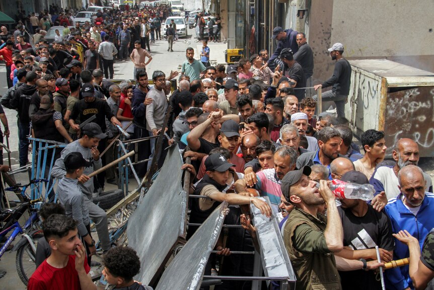 Hundreds of people line up in the street huddled close together