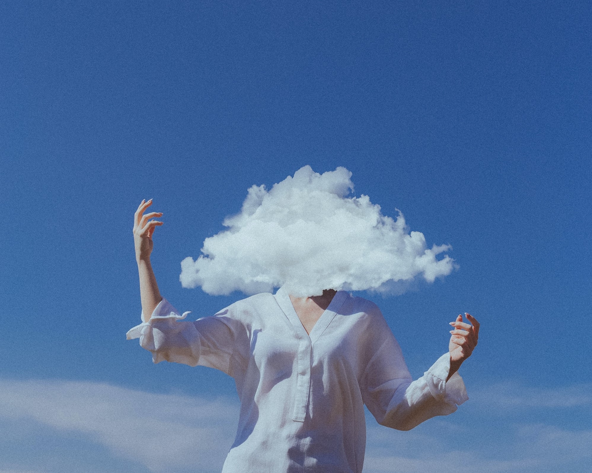 A person standing with their arms raised and their head replaced with a cloud.