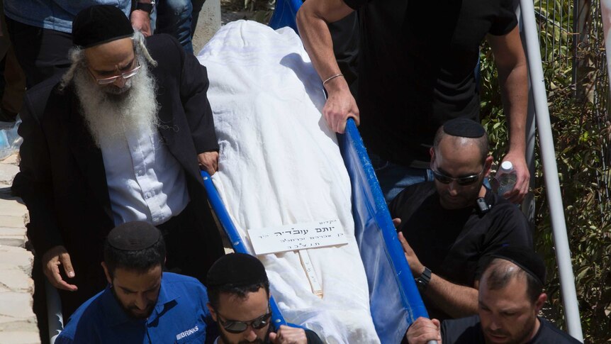 Men are seen carrying a body during a funeral procession.