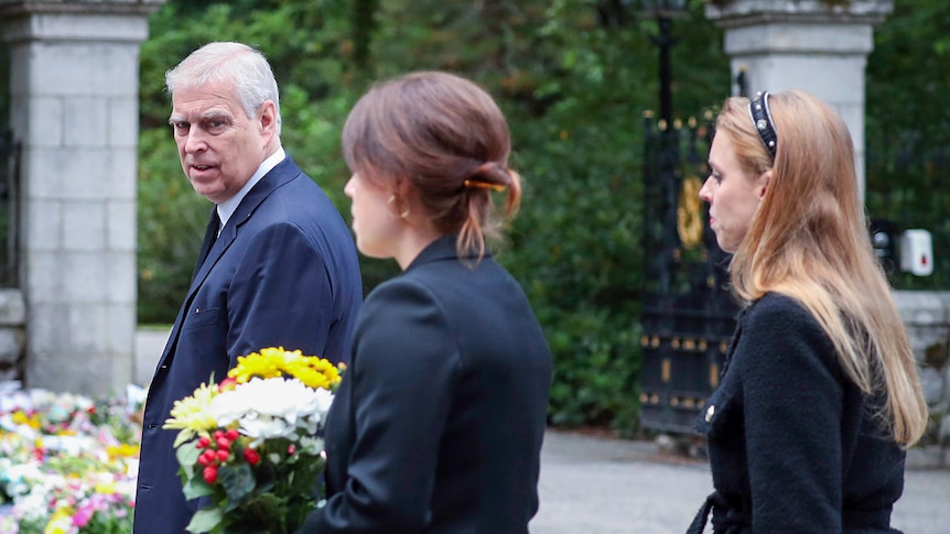 Prince Andrew walks with Eugenie and Beatrice. Eugenie is clutching a big bouquet of flowers