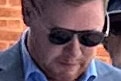 A man wearing sunglasses looks down towards the ground