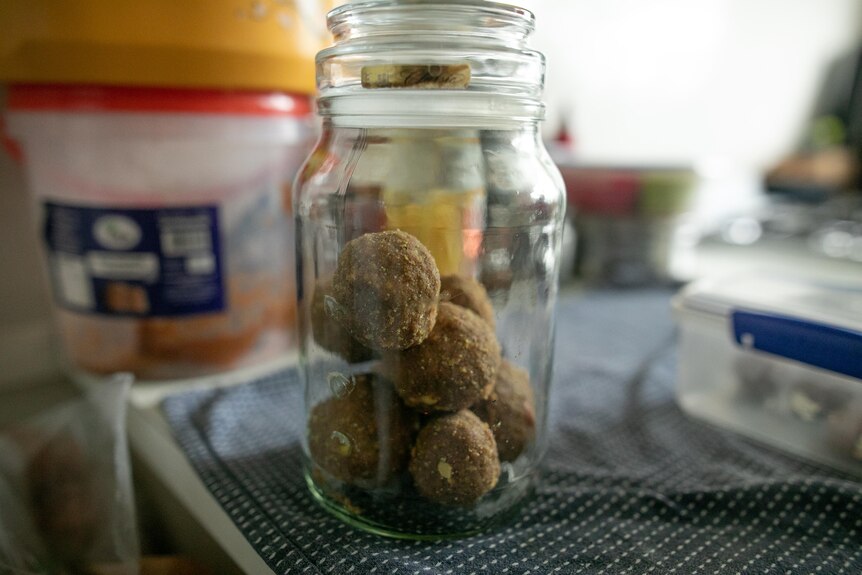 A glass jar with what looks like protein ball on a kitchen bench.