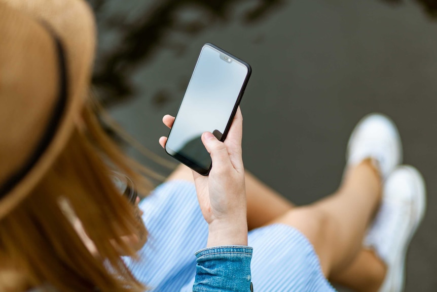 Woman looking at her mobile phone for a story about tips to make moving house easy.