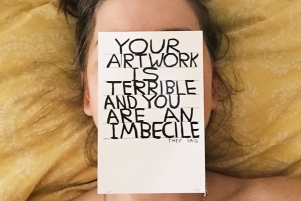 Honor Eastly lays down with a piece of paper over her face saying 'Your artwork is terrible and you are an imbecile'