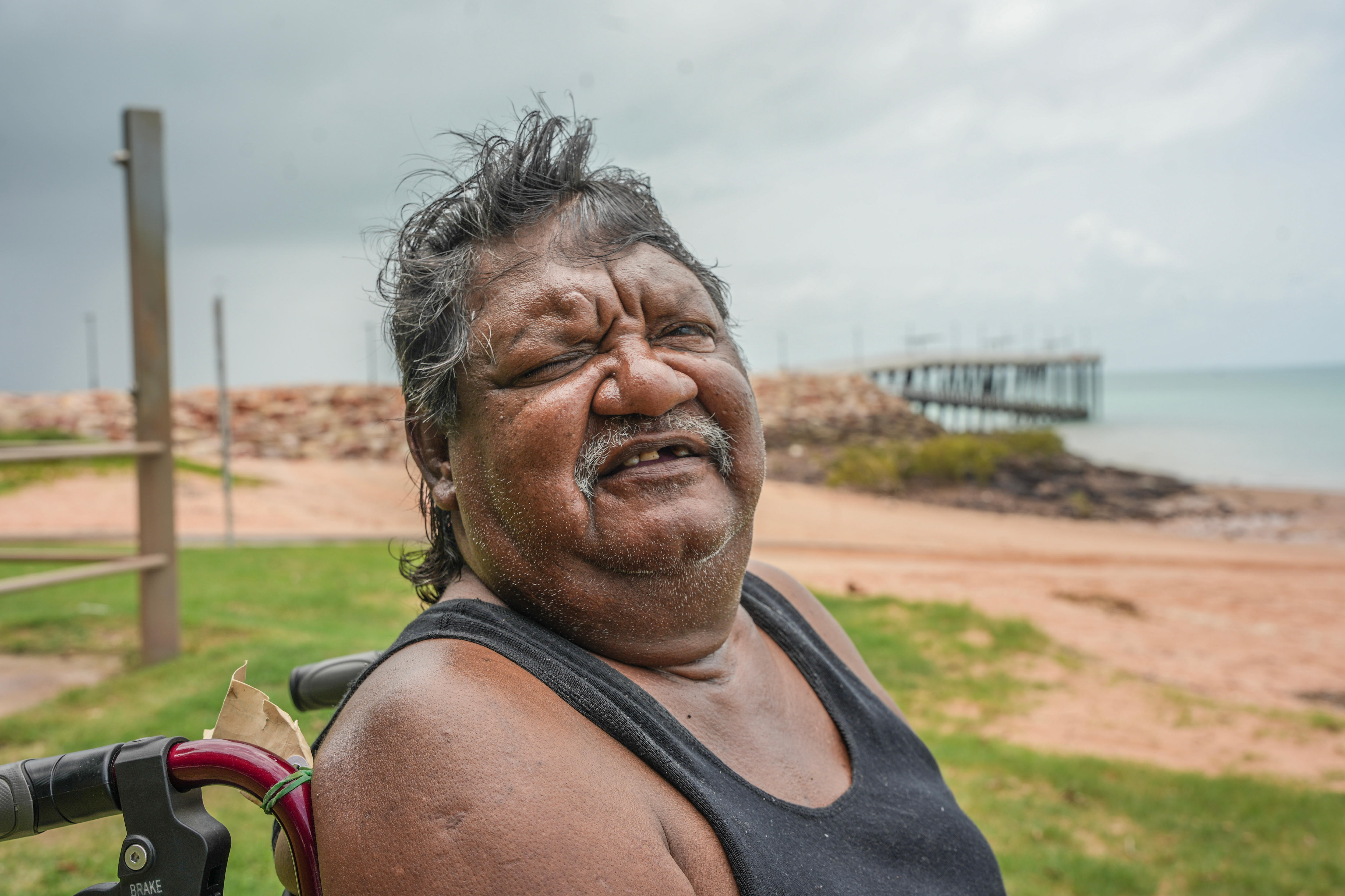 um homem sorrindo para a câmera em uma cadeira de rodas 