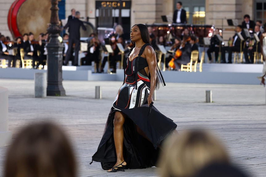 Venus Williams walks a Paris street runway in a black utility style gown