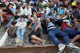 Migrants wait for a train at a railway station