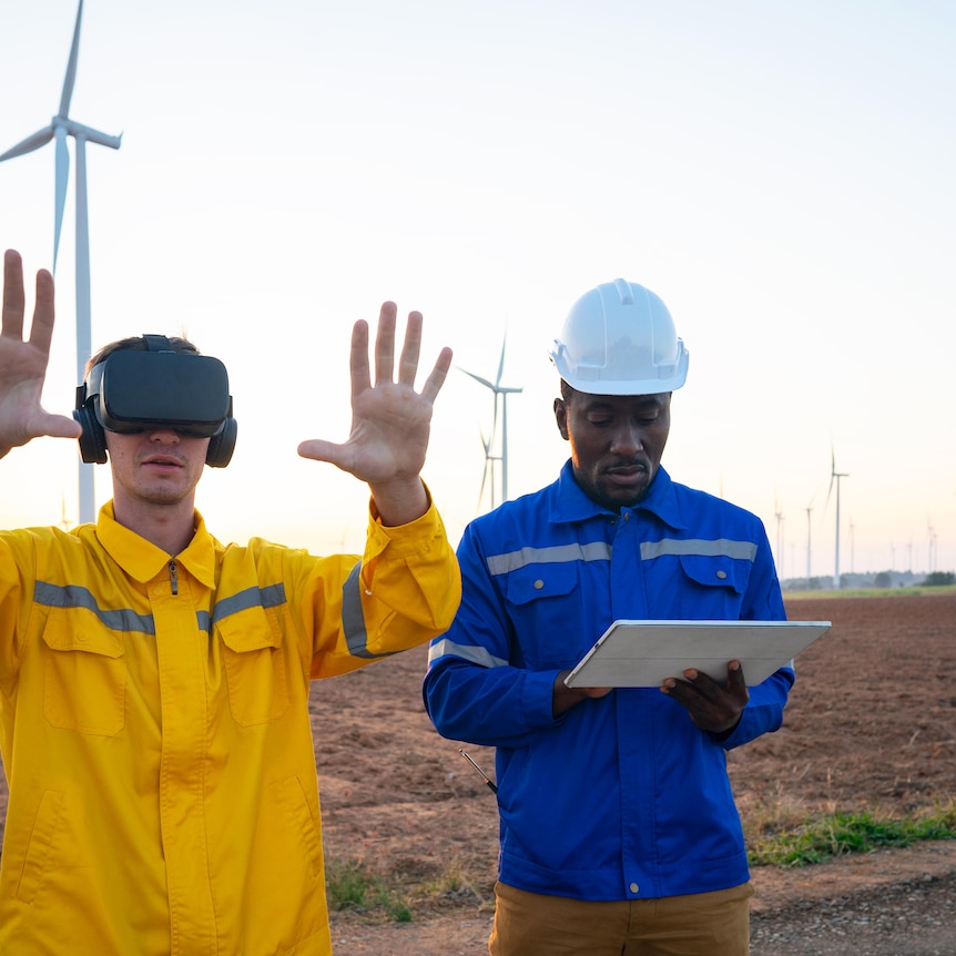 A man stands in front of wind turbines using googles