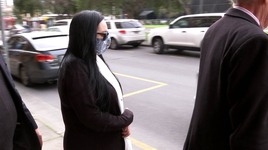 A woman in sunglasses and a mask outside an Adelaide court.