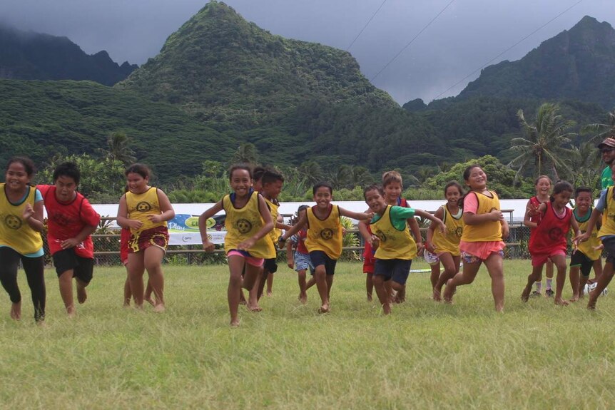 Children running in front of mountains towards the camera