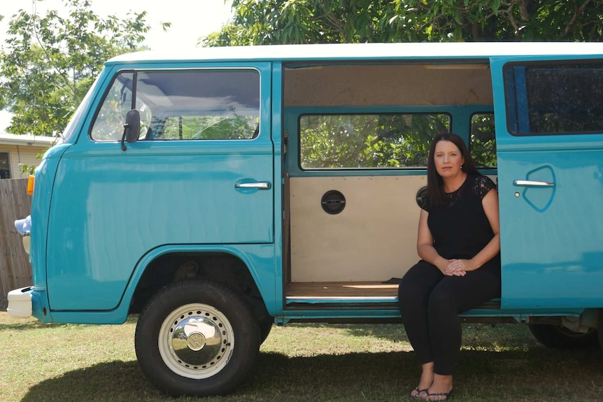 Angela Tallon sitting in Tristan's aquamarine Kombi van.