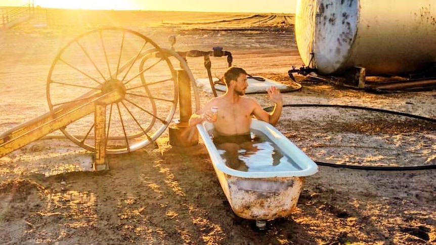 A man sits in a bathtub on a farm