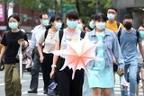 A group of people wearing face masks walks down the street.