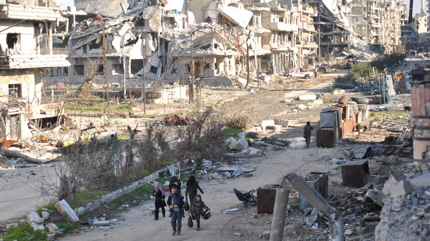 Civilians leave a besieged district of the central Syrian city of Homs