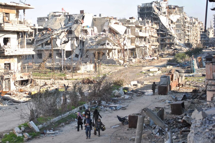 Civilians leave a besieged district of the central Syrian city of Homs