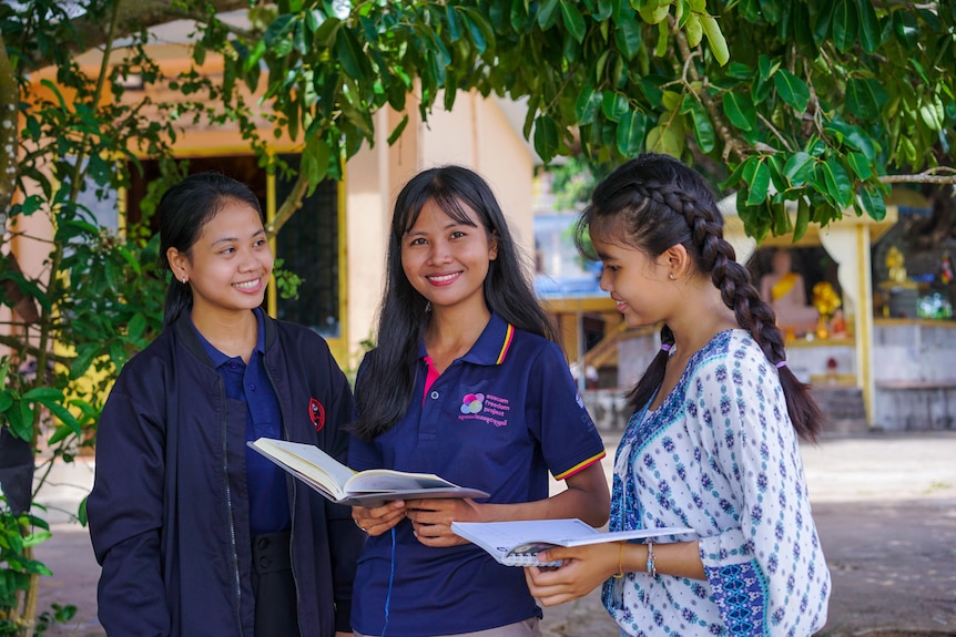 Chatnika Yat holding a book, at Auscam in Cambodia