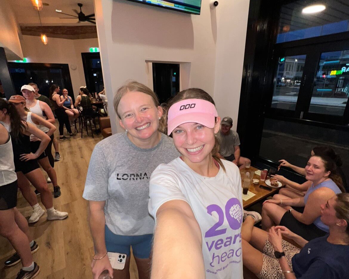 Two women smile at camera in selfie mode inside a pub