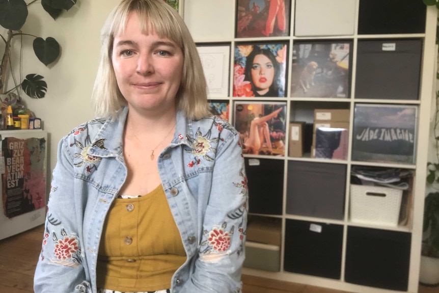 Lorrae McKenna smiles for a photo sitting in front of a number of album covers.