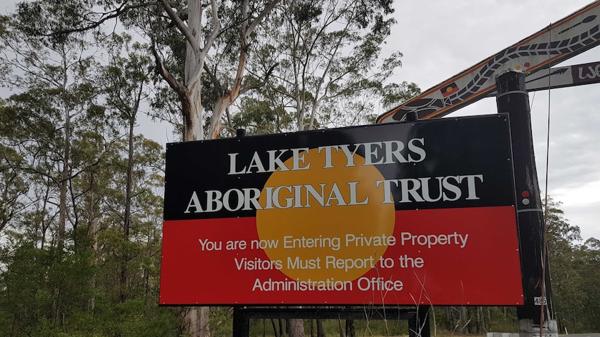 A sign with "Lake Tyers Aboriginal Trust" written on an Aboriginal flag background.