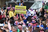 Person holds up sign in protest against the King amongst a crowd of people in London
