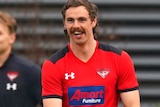Joe Daniher smiles while holding a football at training