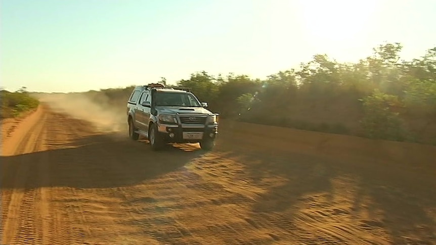 A four-wheel drive car travelling along a dirt road.