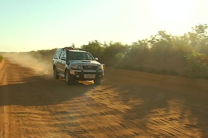 A four-wheel drive car travelling along a dirt road.