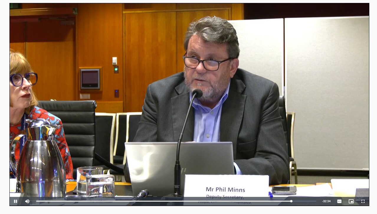 A bearded man speaking into a microphone