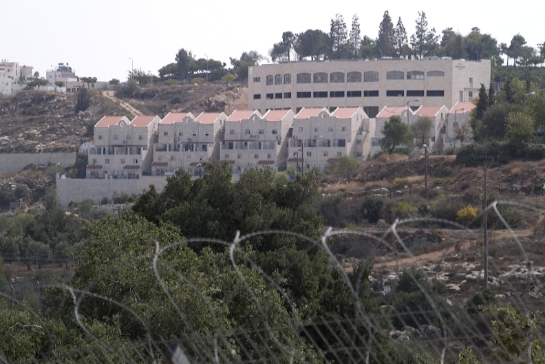 On the other side of razor wire fences, a settlement of houses are built into a hill
