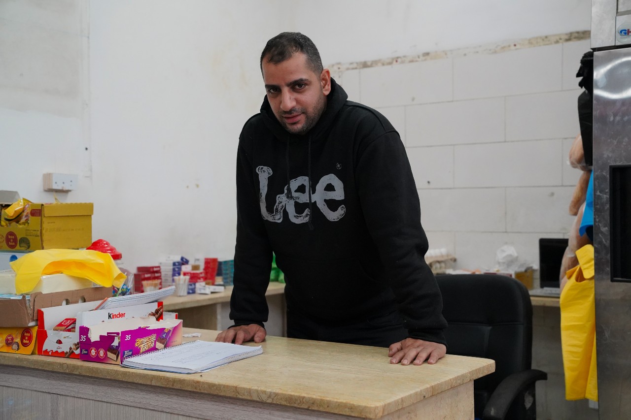 A man leaning on a counter looks at the camera.