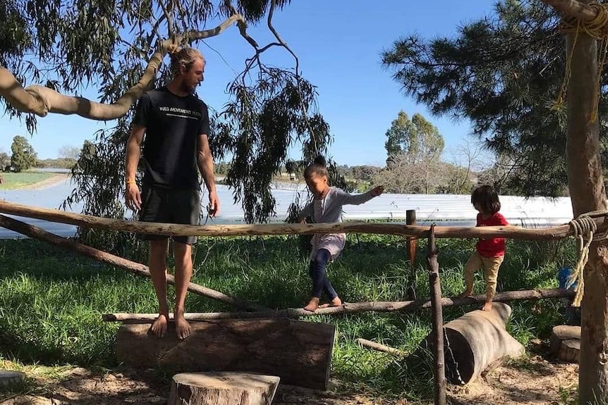 Steve Aldridge at wild school with two children as they walk along an obstacle course.