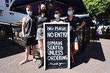 People stand out the front of a pub which says 'No mask, no entry'