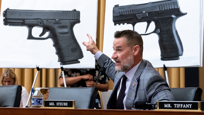 A man points to pictures of guns as he compares different models of firearms as the House Judiciary Committee.