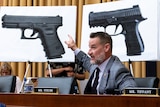 A man points to pictures of guns as he compares different models of firearms as the House Judiciary Committee.