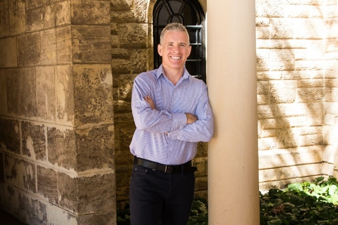 a man in a business shirt smiles at the camera