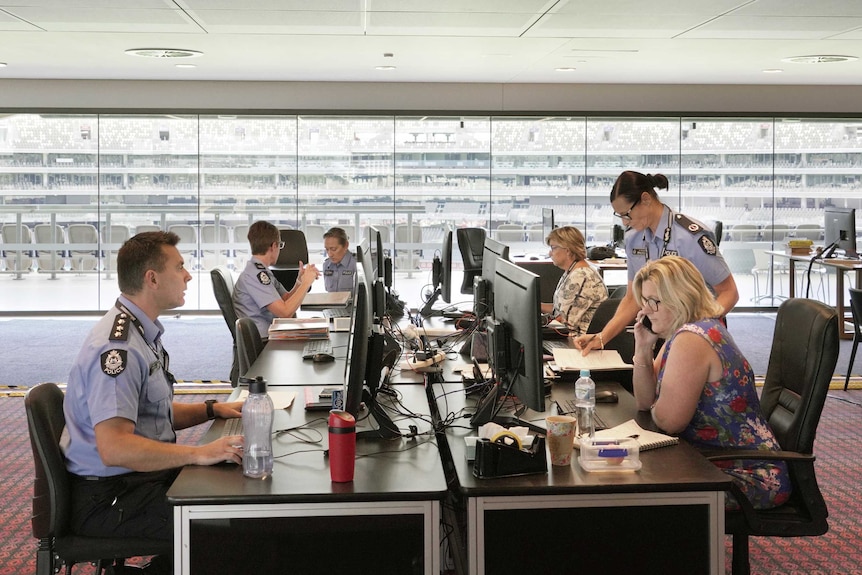 Police in uniform sit at desks with computers